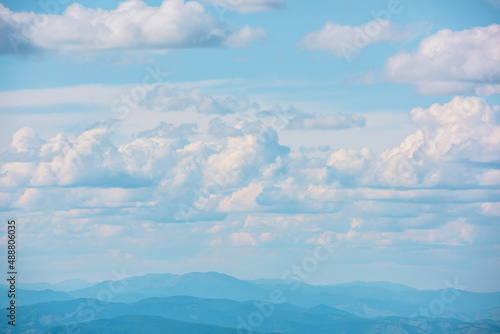 Scenic minimalist landscape with cumulus clouds in blue sky. Beautiful minimal view to cloudy sky. Simple minimalism with white clouds in blue sky. Colorful sky scenery. Atmospheric day cloudscape.