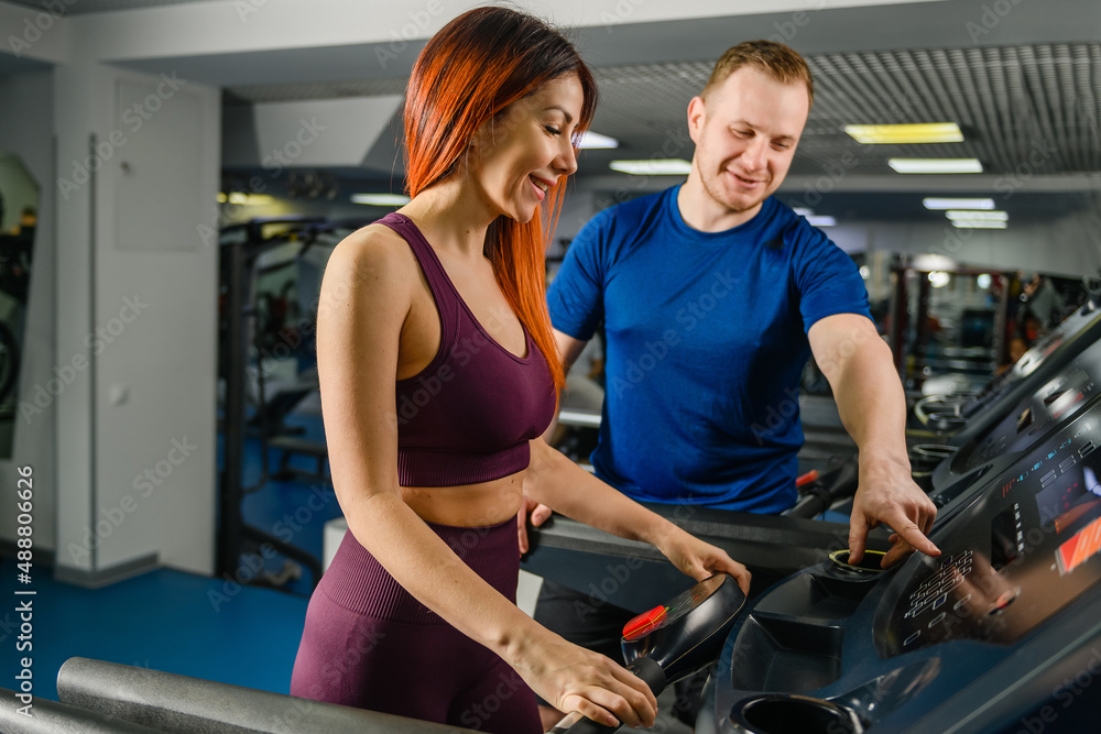 Trainer adjust, press buttons at treadmill jogging track for pretty woman, gym customer, sportive lifestyle Trainer adjust, press buttons at treadmill jogging track for pretty woman, gym customer, sportive lifestyle