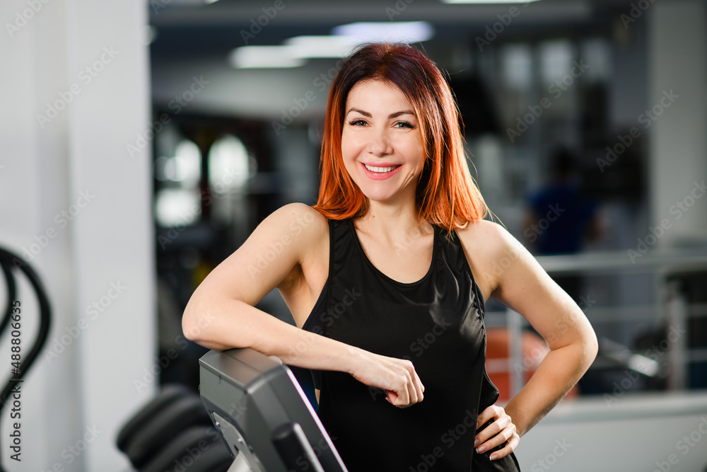 Portrait of a sportive fit woman in gym interior, beautiful healthy female posing at modern sports hall with equipment Portrait of a sportive fit woman in gym interior, beautiful healthy female posing at modern sports hall with equipment