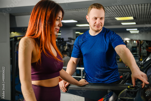 Trainer adjust, press buttons at treadmill jogging track for pretty woman, gym customer, sportive lifestyle