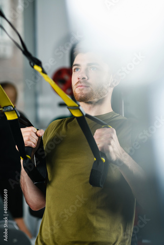 Young man portrait during gym exercises, fit handsome male workout for strong hands with modern equipment indoors