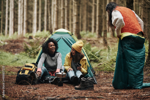 Foto Friends laughing while camping in a forest