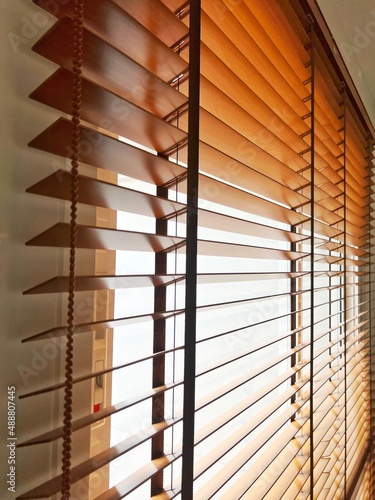 Brown wooden blinds on windows of rooms inside house.