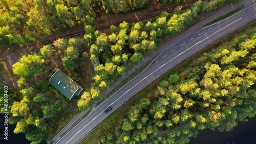 Aerial view of car driving through forest and lake. Beautiful scandinavian road. Nordic forest and lake landscape. Car driving through pine forest.