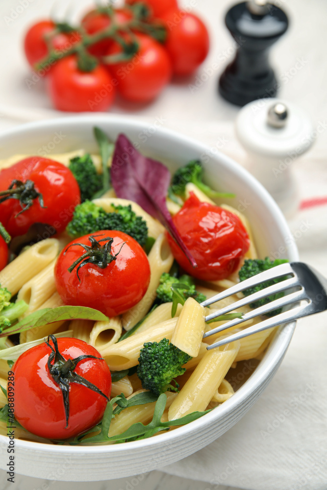 Bowl of delicious pasta with tomatoes, arugula and broccoli on white table, closeup Bowl of delicious pasta with tomatoes, arugula and broccoli on white table, closeup