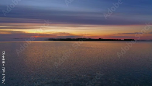 Lake view at sunset, afterglow in the sky and reflection of trees by the lake in the water, Lake Paijanne in Finland	