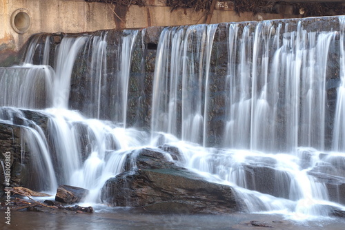 The waterfalls are white with the foam and flowing into the river.