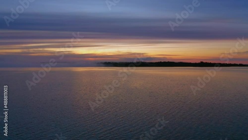Lake view at sunset, afterglow in the sky and reflection of trees by the lake in the water, Lake Paijanne in Finland