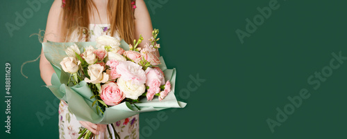 Woman holding a beautiful bouquet with flowers on green background. Front view. Valentine's, women's, mother's day, love concept. 8th of march. Banner