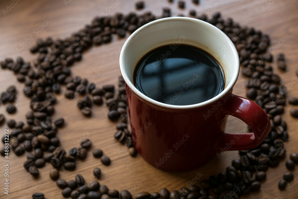 Selective focus of a cup of coffee with a roasted coffee beans at the background. Selective focus of a cup of coffee with a roasted coffee beans at the background.