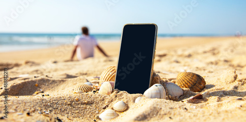 mobile phone on the beach and people silhouette relaxing