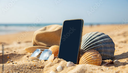 Fototapeta Naklejka Na Ścianę i Meble -  summer holiday concept with smartphone, sunglasses and hat on the beach
