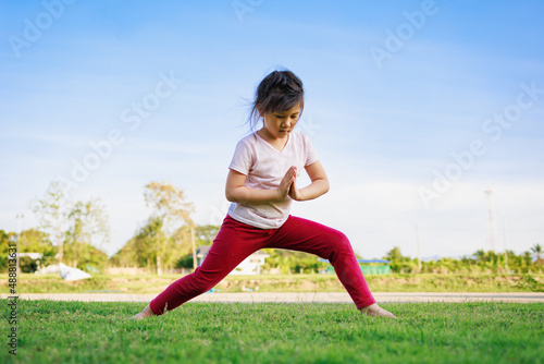 Children meditation with yoga pose on green grass field. Outdoors activity for kids to practicing yoga  children can learn how to exercise  develop confidence and concentrate better.