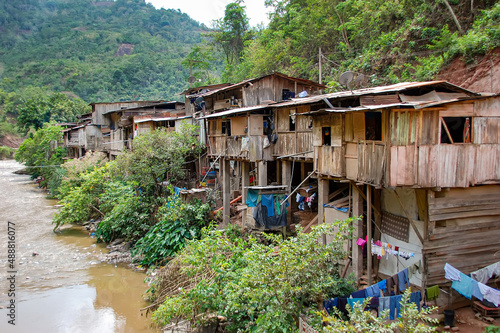 Fragile houses in Chanchamayo river in Peru. Social issues, danger of flood and building collapse, natural disaster, poverty. Shack in riverbank made with wood. photo