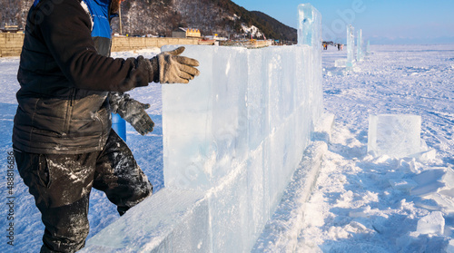 Sculptor builds a wall from an ice block on Lake Baikal.
