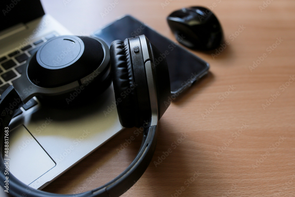 Headphones on the laptop with smartphone and a mouse on a table Headphones on the laptop with smartphone and a mouse on a table