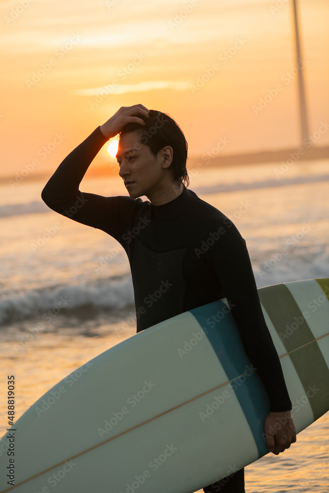 Fototapeta premium 朝の海でサーフィンをする男性