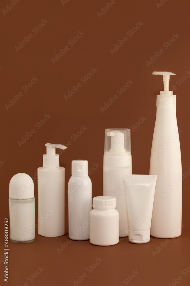 different white bottles and tubes for cosmetics on a brown background with space for text different white bottles and tubes for cosmetics on a brown background with space for text