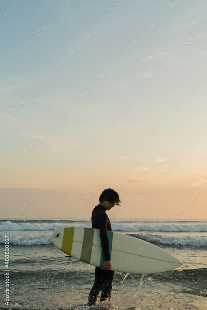 Fototapeta premium 朝の海でサーフィンをする男性