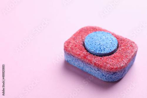 Dishwasher detergent tablet on pink background, closeup. Space for text