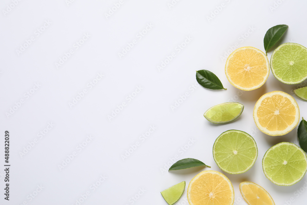 Fresh ripe lemons, limes and green leaves on white background, top view Fresh ripe lemons, limes and green leaves on white background, top view