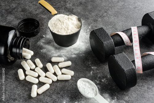 protein scoop, creatine capsules and dumbbells with measuring tape. The concept of the usefulness of sports nutrition.