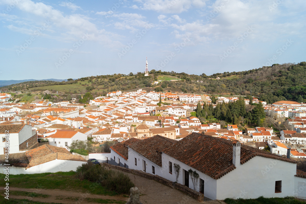 View of the beautiful village of Aracena (Andalusia, Spain). Village with white-walled houses and tiled roofs surrounded by nature. Village on a hill illuminated on a sunny day.