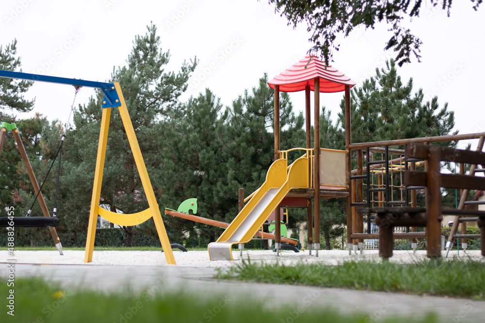 The outdoor playground in the daytime has a backdrop of green trees and blue skies. The outdoor playground in the daytime has a backdrop of green trees and blue skies.