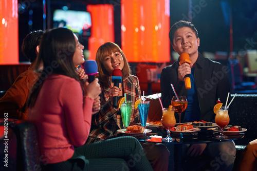 Asian friends enjoying friendship together in karaoke bar