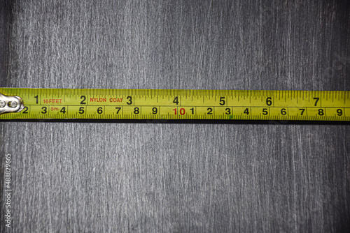 The yellow tape measure is measured in centimeters, measuring the size of a gray-black steel plate