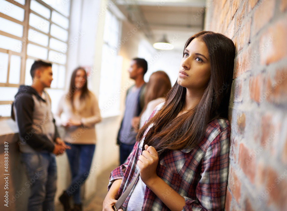 Loving life on campus. Shot of a beautiful young female student looking bored while leaning against a brick wall on campus. Loving life on campus. Shot of a beautiful young female student looking bored while leaning against a brick wall on campus.