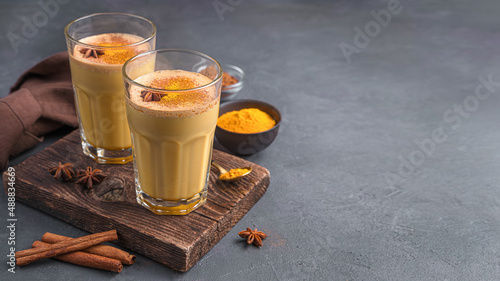 Latte with turmeric, golden milk with cinnamon and anise on a gray-brown background.