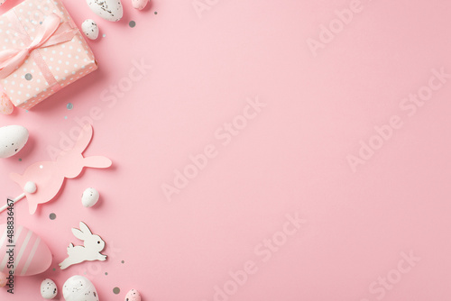 Top view photo of easter decorations giftbox shiny confetti easter bunnies pink and white easter eggs on isolated pastel pink background with empty space © ActionGP