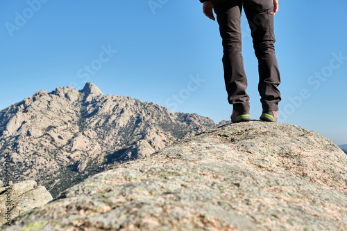 Legs of woman hiker standing on a rock contemplating the mountains. © roberjzm