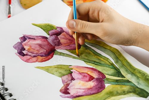 Woman painting tulips in sketchbook, closeup view #488838053