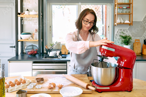 Εκτύπωση καμβά Woman wearing apron baking cookies in a cozy kitchen