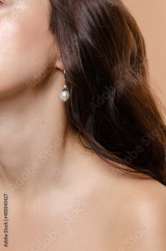 Woman studio beauty portrait closeup with pearl earring jewellery. Glowing natural skin, skin care, UV sun protection.