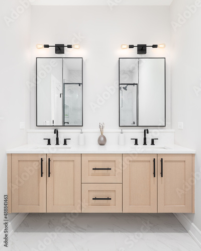 Fototapete A modern bathroom with a wooden vanity cabinet, black faucets, white marble countertop, and black rimmed square mirrors