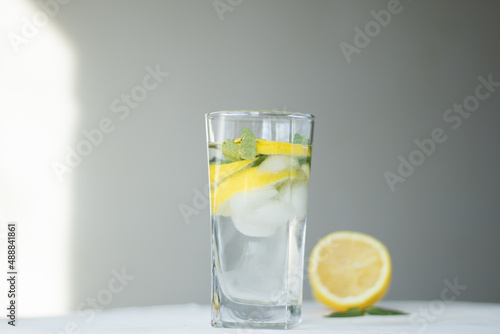 glass of water with lemon. homemade cold refreshing drink or water with ice on rustic wood background. Copy space. summer drinks. Two glass with lemonade or mojito cocktail with lemon and mint.