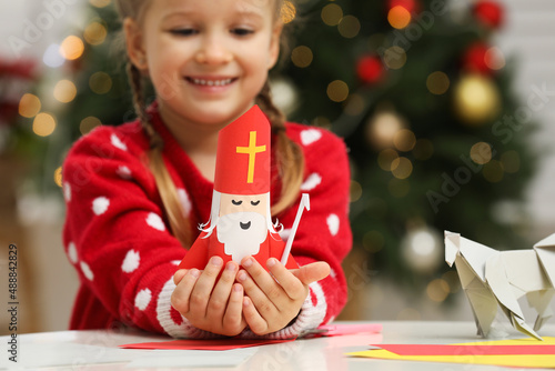Cute little girl with paper Saint Nicholas toy at home, focus on hands photo
