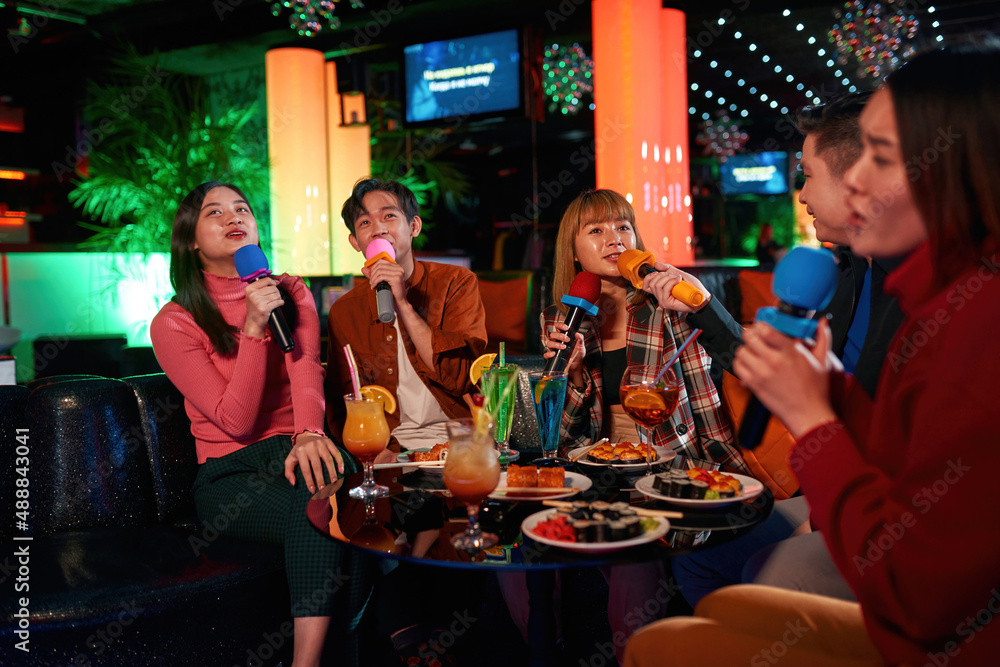Drinking cocktails at party and enjoying friendship together in karaoke bar