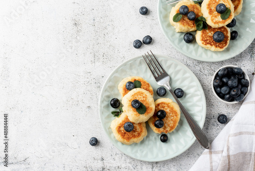 Cottage cheese fritters with blueberries on concrete background with copy space