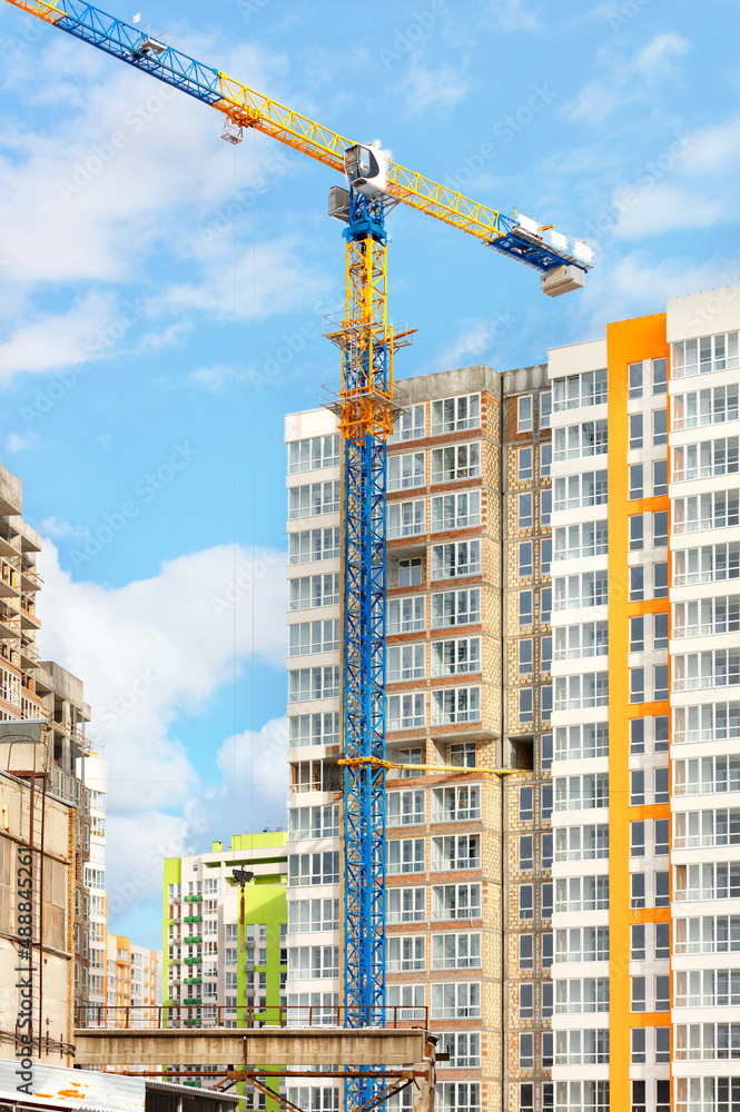 A tower crane towers majestically on the construction site of a modern high-rise residential building.
