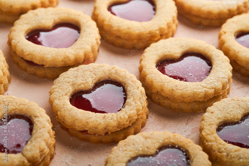 Traditional Linzer cookie with strawberry jam and powder sugar on pink beautiful background. Top view. Traditional homemade Austrian sweet dessert food on Valentines Day. Holiday snack concept.