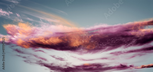 Magnificent long purple and orange powder explosion on blue background