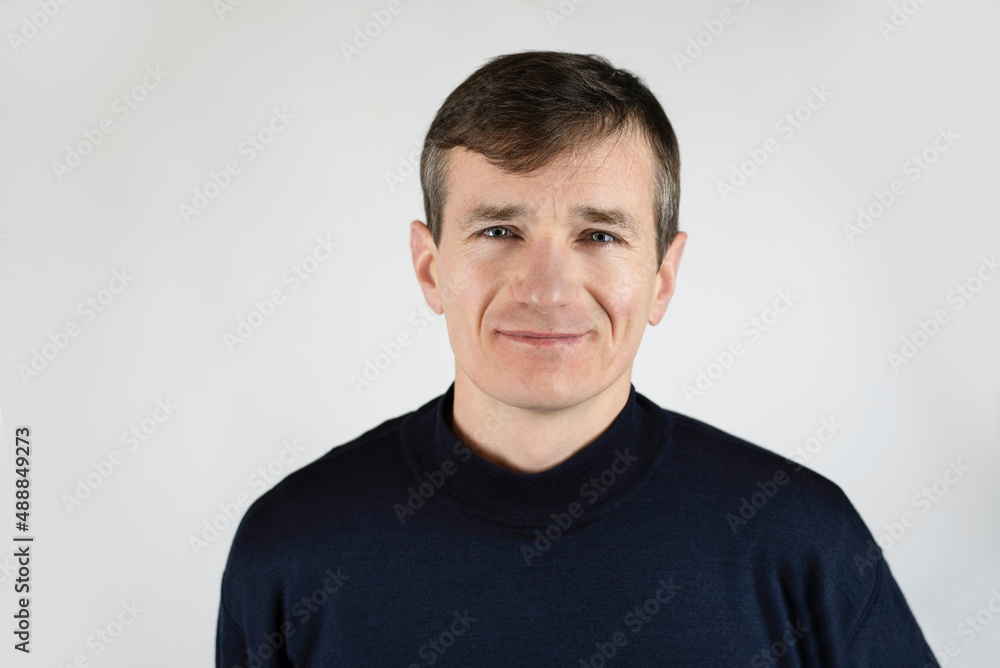 Mature slender man smiling on a light background, hair begins to turn gray, man is happy, not afraid of the crisis of middle age Mature slender man smiling on a light background, hair begins to turn gray, man is happy, not afraid of the crisis of middle age