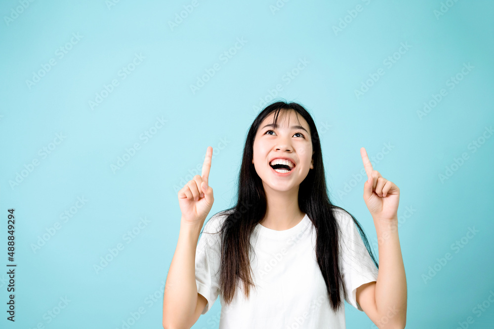 Studio shot of happy female pointing up at copy space. Studio shot of happy female pointing up at copy space.