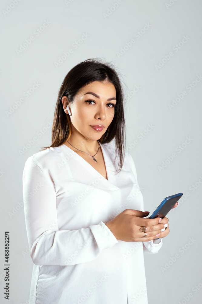 portrait of a young brunette woman speaks on the phone, office wear white blouse, isolated white background. business concept portrait of a young brunette woman speaks on the phone, office wear white blouse, isolated white background. business concept