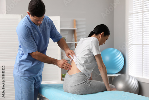 Photos Orthopedist examining woman's back in clinic. Scoliosis treatment