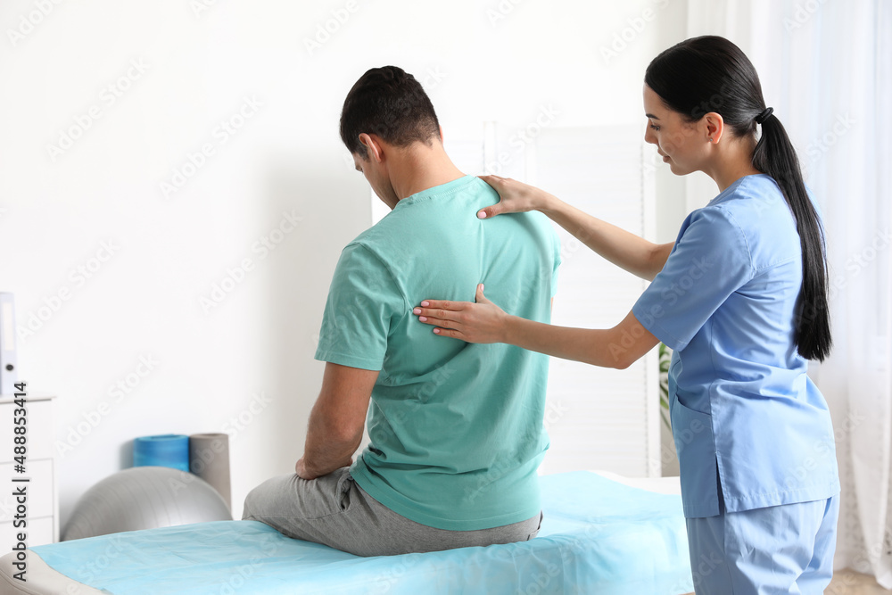 Orthopedist examining man's back in clinic. Scoliosis treatment Orthopedist examining man's back in clinic. Scoliosis treatment